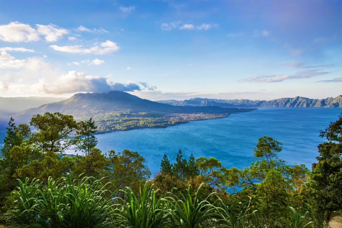 Family Paradise In Bali Aerial view of Mount Agung volcano overlooking blue ocean waters and lush green coastline in Bali, Indonesia