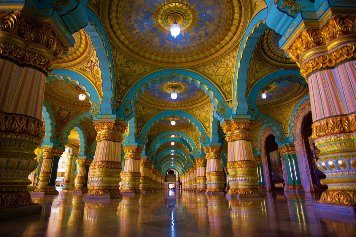 Natures Embrace Karnataka and Kerala Escape Ornate temple corridor with golden carved columns, turquoise arches, and illuminated domed ceiling in Kerala or Karnataka sty