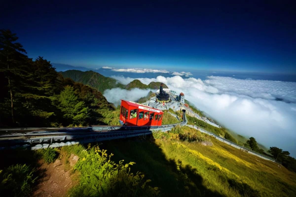 Red mountain railway car on tracks with mountain peak, temple, and sea of clouds at Fansipan peak in Sapa, Vietnam