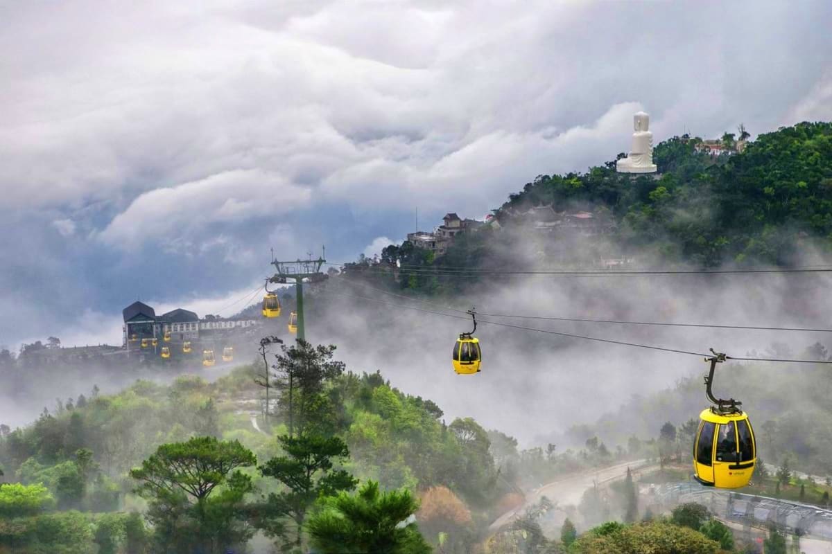 Vietnam Cultural Journey for Families Yellow cable cars suspended over misty mountainous landscape with ancient temple and buildings perched on hilltop in Vietnam