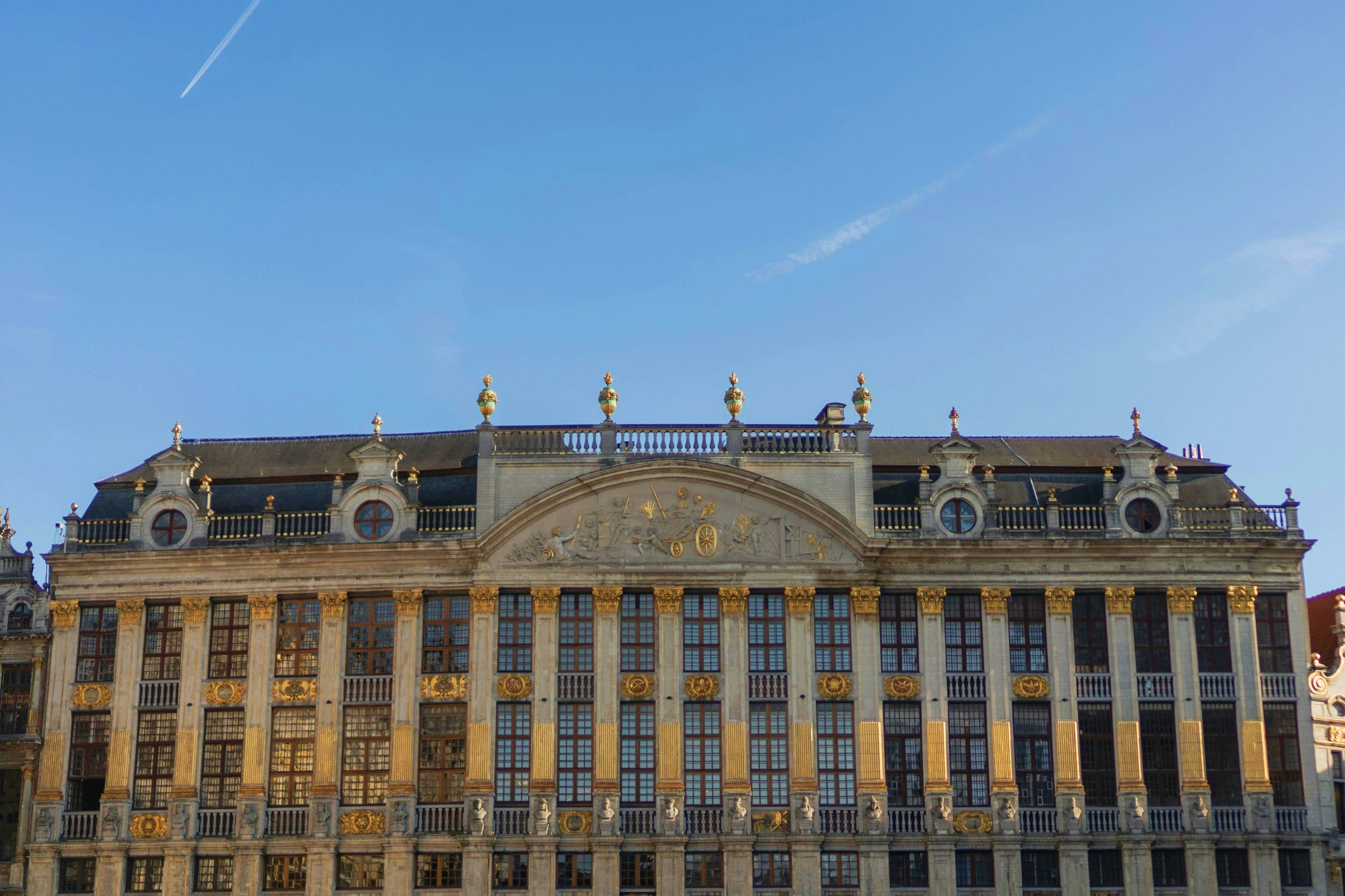 Belgium Historic ornate building with gold decorative elements and mansard roof in Brussels, Belgium, under clear blue sky