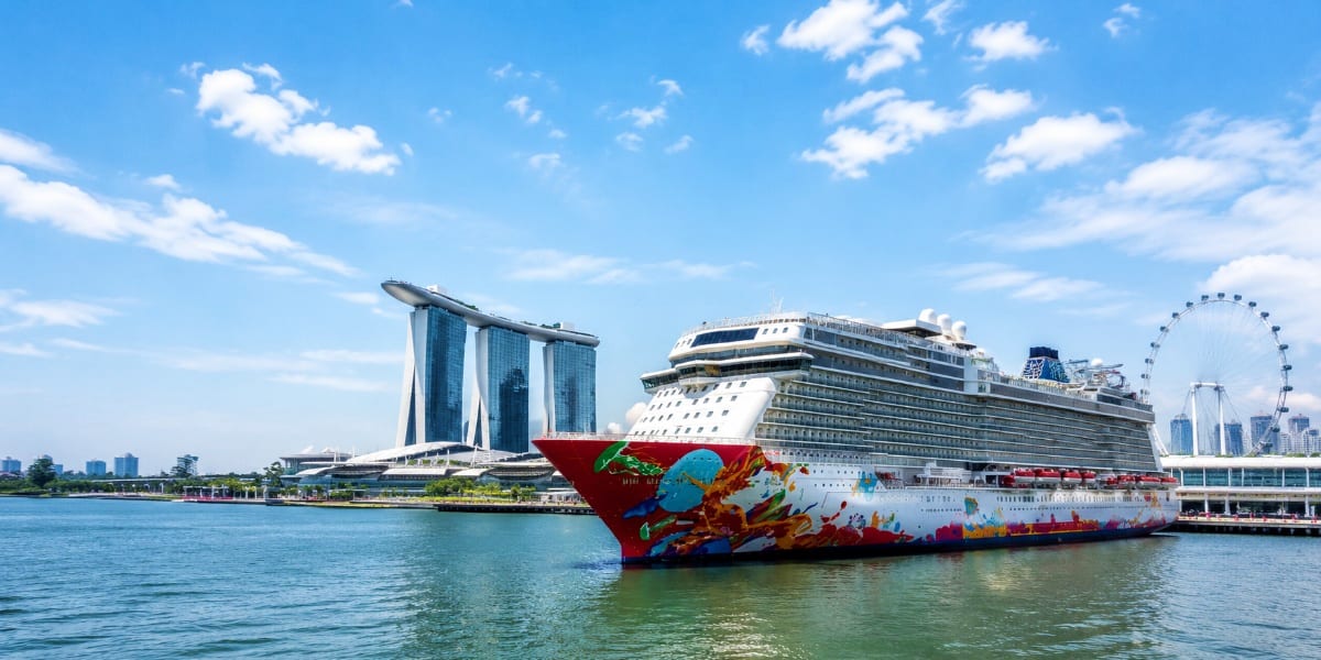 Large cruise ship docked at Marina Bay Singapore with iconic Marina Bay Sands hotel and Singapore Flyer observation wheel vis
