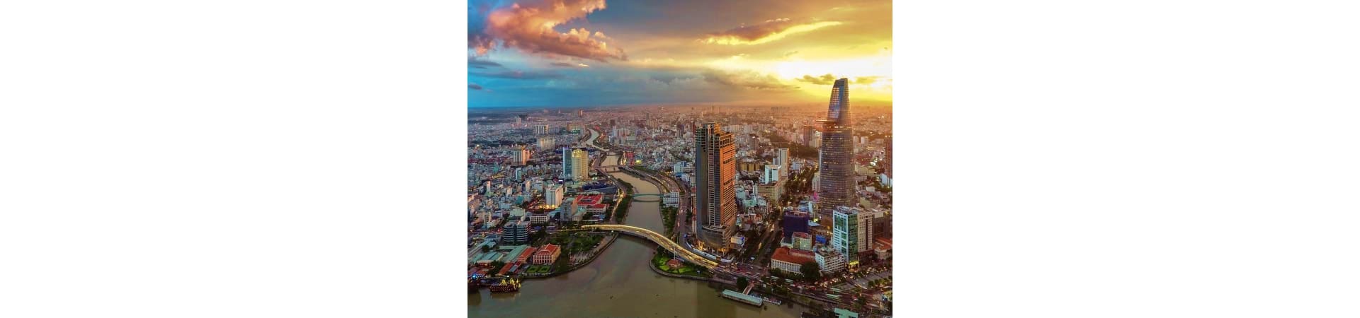 Aerial view of Ho Chi Minh City skyline at sunset with Bitexco Financial Tower and Saigon River winding through the cityscape