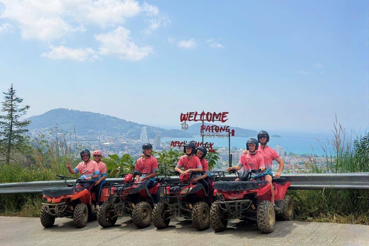 ATV and Buggy Group of tourists on red ATVs at Welcome to Patong sign overlooking Patong Beach and coastal city landscape