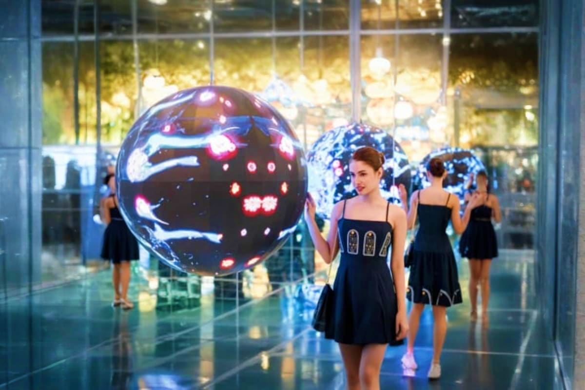 Space and Time Cube Thailand Visitors in black dresses viewing an illuminated interactive LED sphere display with glowing patterns at Space and Time Cube