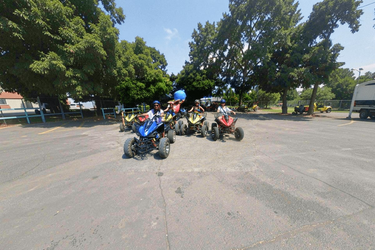 Boracay ATV and Buggy Car Adventure Group of riders on colorful ATVs and buggy cars lined up on a paved outdoor lot surrounded by trees under clear sky