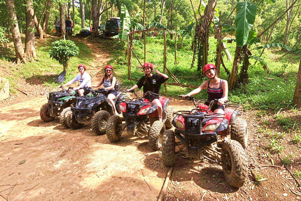 Boracay ATV and Buggy Car Adventure Four people on ATVs and buggy cars on a muddy jungle trail surrounded by lush green forest and trees
