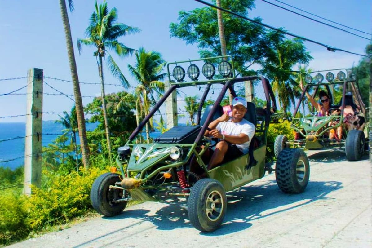 Boracay ATV and Buggy Car Adventure Man driving a green buggy on a coastal road with palm trees and ocean view in Boracay during an ATV adventure tour