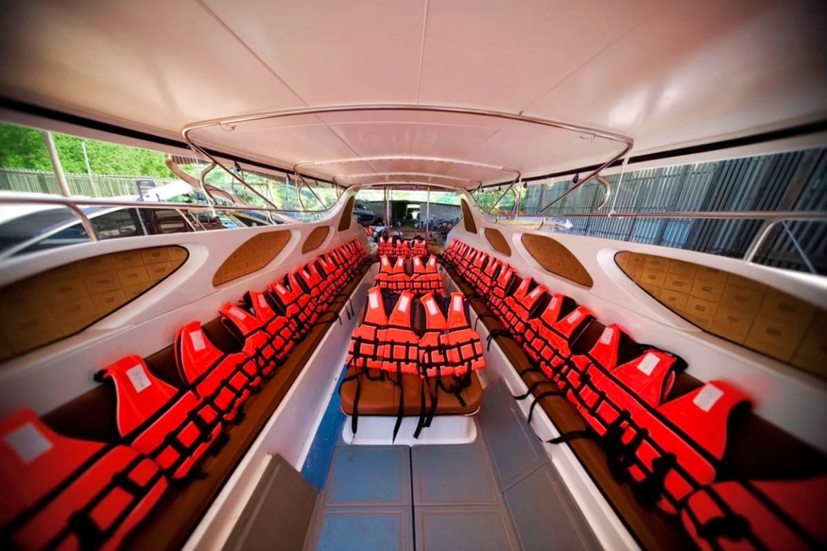 7 Island tour by Speed boat Interior of a speedboat with rows of red seats facing forward under a tan canvas canopy, ready for island tour passengers