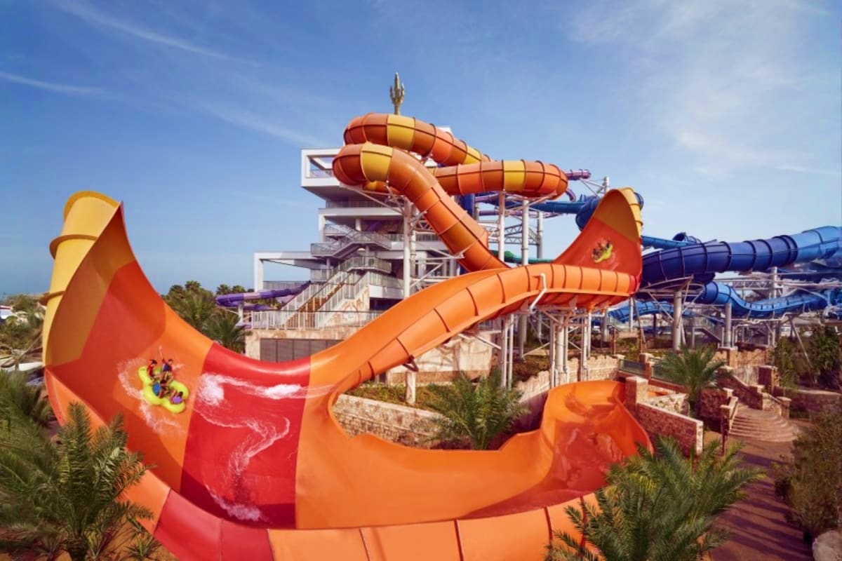 Man sliding down yellow water slide at Atlantis Aquaventure theme park with splashing water and tropical scenery (5)
