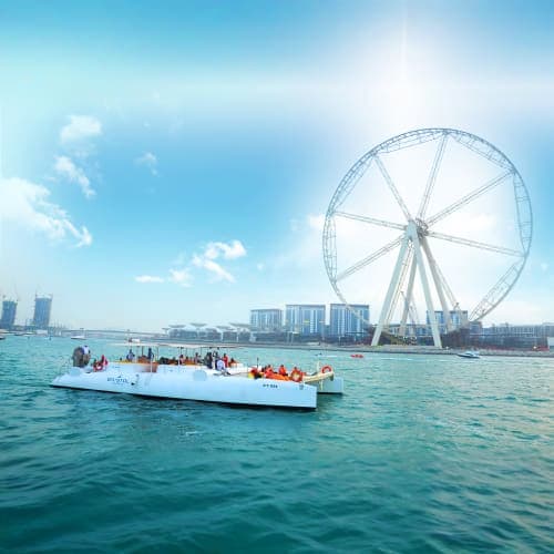 Bristol Sharing Charter Dubai White yacht with passengers sailing near the Dubai Eye Ferris wheel on turquoise water with city skyline in background