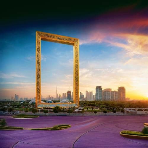 Golden Dubai Frame monument with cityscape skyline view at sunset, featuring modern architecture and landscaped plaza in fore