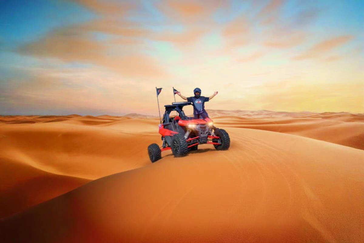 Group of tourists posing with yellow and black dune buggies on orange sand dunes under blue sky in Dubai desert (3)