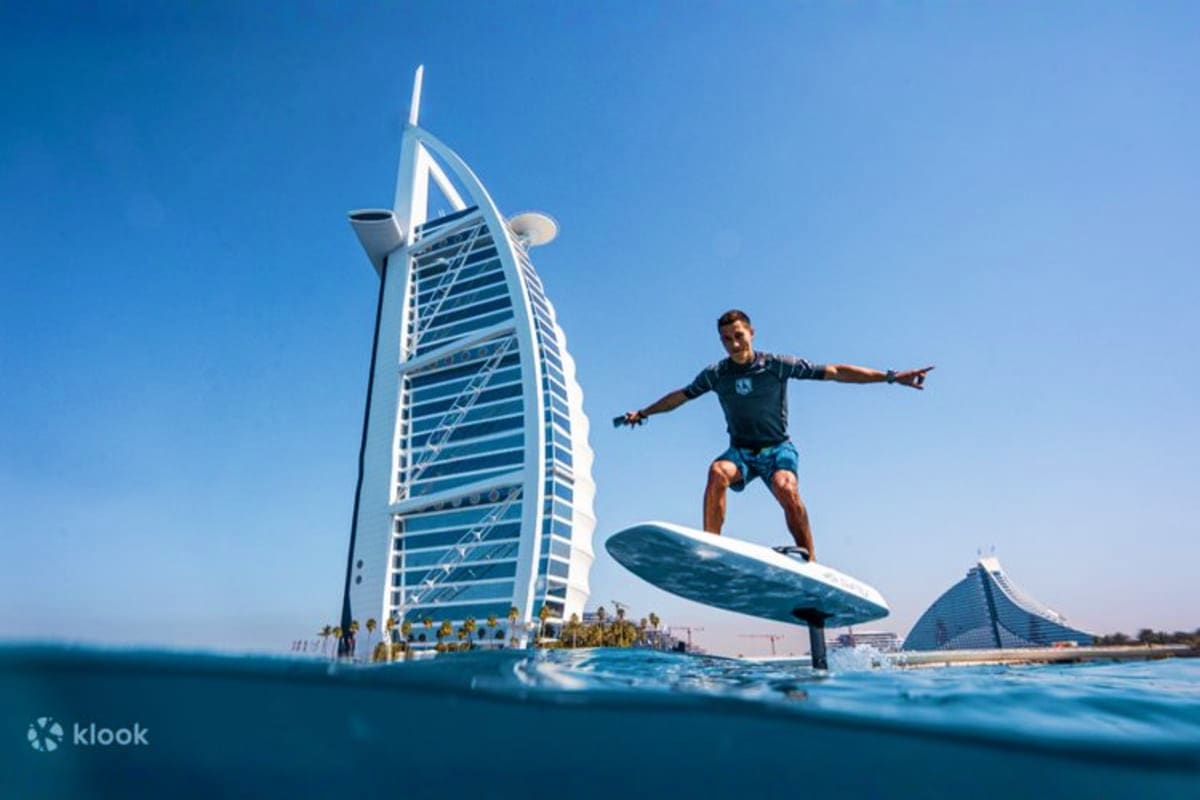 Man foil surfing in turquoise water with Burj Al Arab luxury hotel in background, Dubai