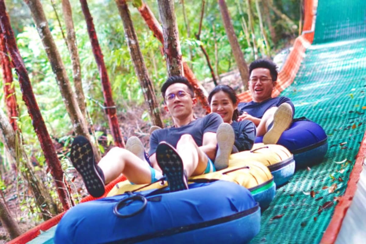 Escape Theme Park Penang Group of four people enjoying a bobsled ride through a forested track at Escape Theme Park Penang
