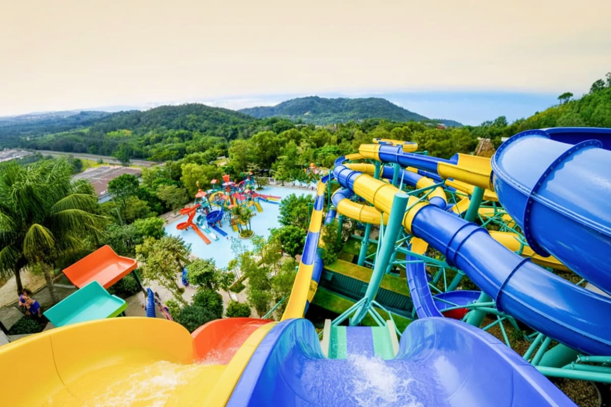 Escape Theme Park Penang Aerial view of Escape Theme Park Penang with colorful water slides, pools, and lush green mountains in background