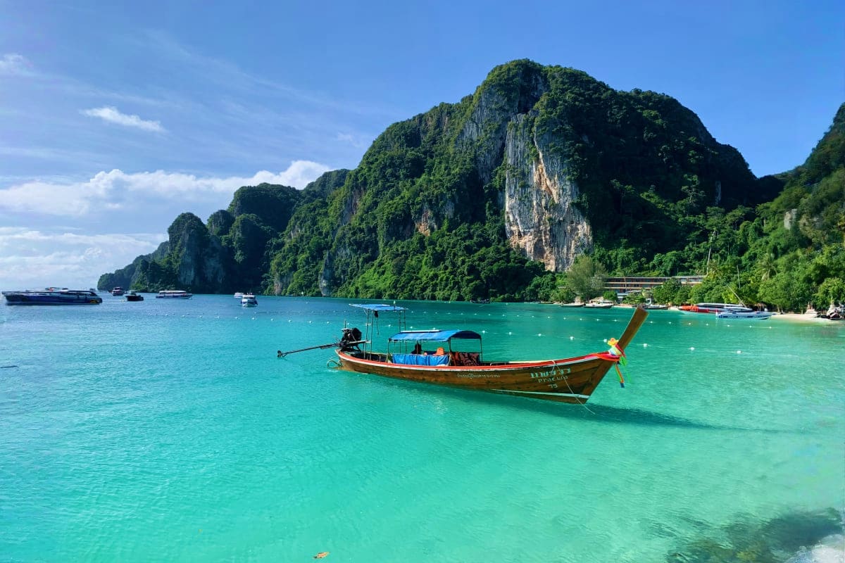 James Bond Island on Long Tail Boat Traditional long tail boat anchored in turquoise water with dramatic limestone cliffs and lush vegetation at James Bond Islan