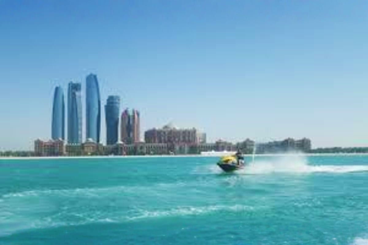 Jet ski Experience in Abu Dhabi Jet ski rider on turquoise water with Abu Dhabi skyline and modern skyscrapers in background under clear blue sky