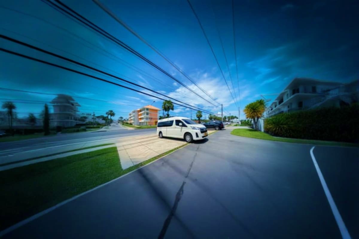 Two Way Transfers for Sunway Lagoon White van parked on residential street with apartment buildings, palm trees, and power lines under blue sky