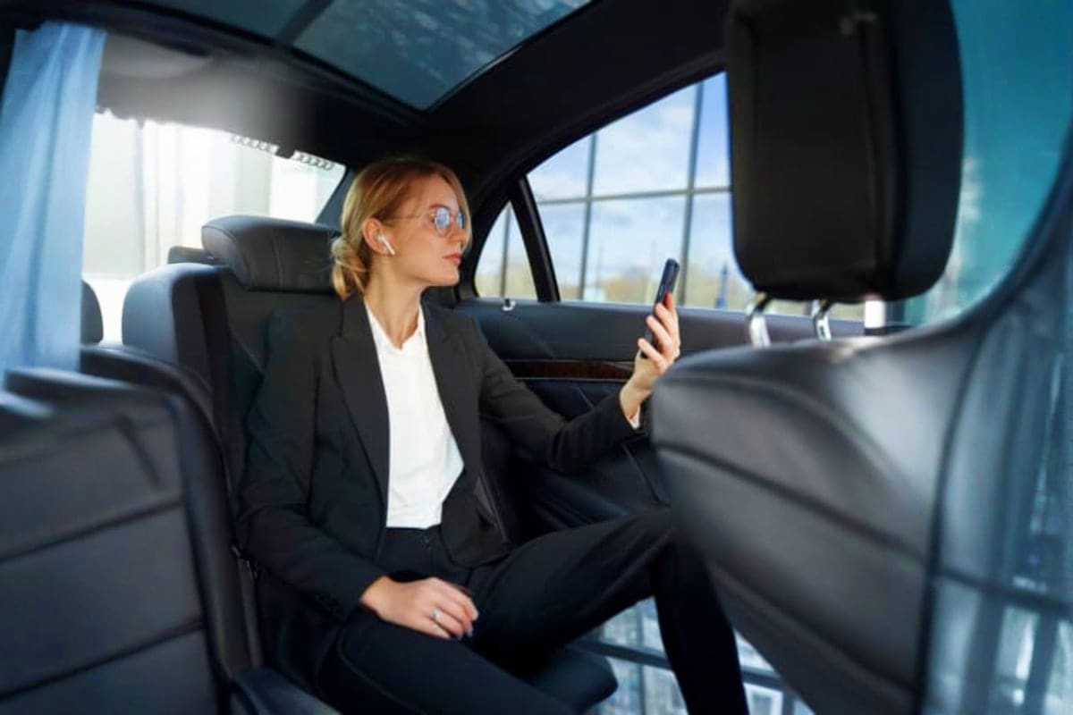 Two Way Transfers for Sunway Lagoon Businesswoman in black suit and sunglasses sitting in back seat of car holding mobile phone during transfer