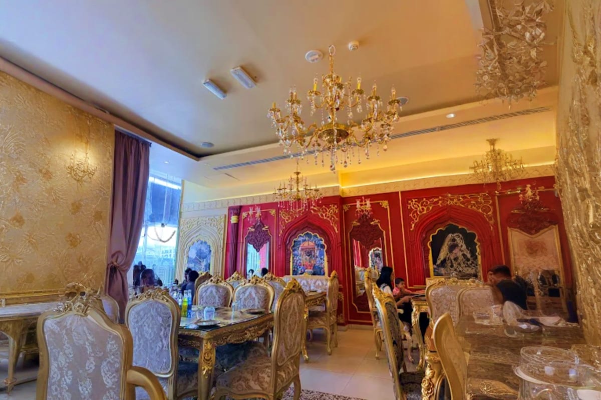 Luxurious dining hall at Mysore Palace Dubai with ornate gold chairs, crystal chandeliers, and red decorative wall panels wit (5)