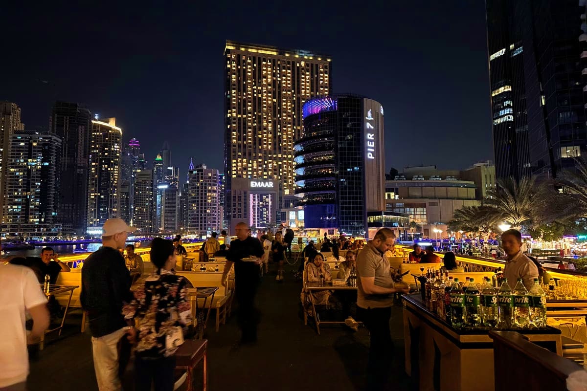 Luxury white yacht anchored at night with illuminated Dubai Marina skyscrapers and blue-lit waterfront buildings in background (3)