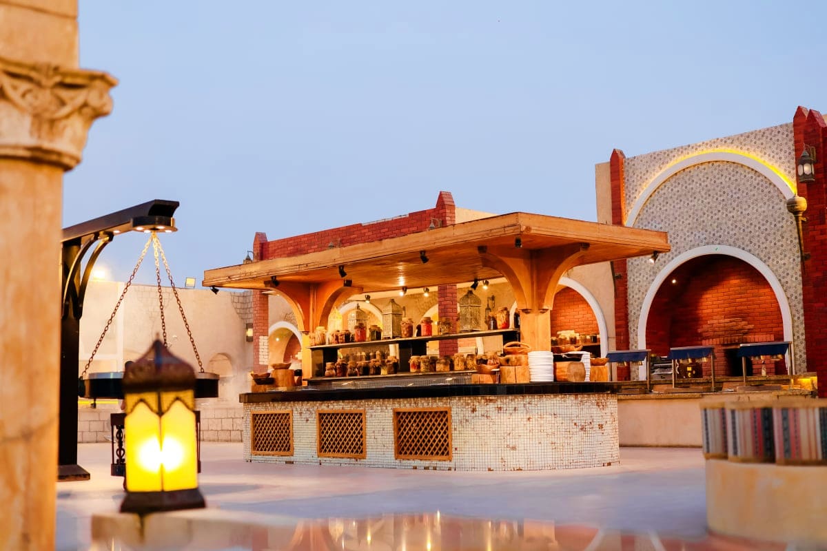 Illuminated brick marketplace pavilion with wooden pergola and arched architecture at dusk, featuring lantern in foreground