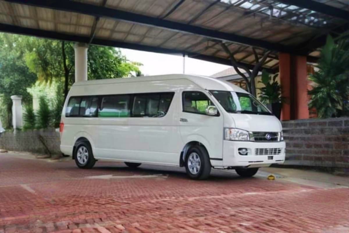 Penang Hotel to Penang Ferry Centre Private Transfers White passenger van parked under covered carport with brick paving and tropical plants visible in background