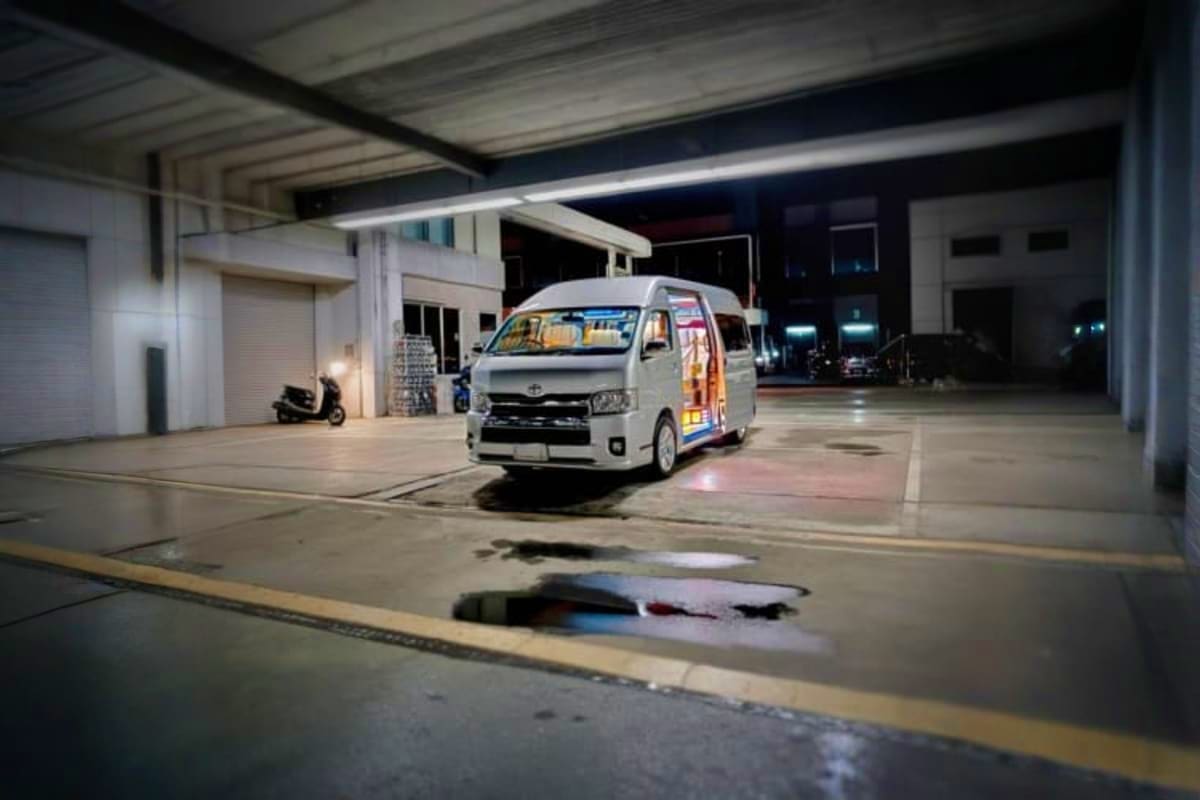 White minivan parked in covered parking area at night, ready for hotel to ferry terminal transfer service