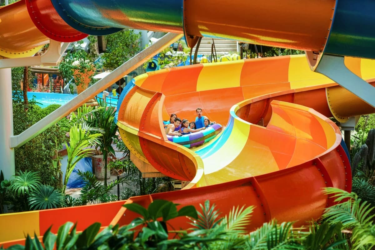 Sunway Lagoon Family riding orange and yellow water slide at Sunway Lagoon theme park with tropical plants visible