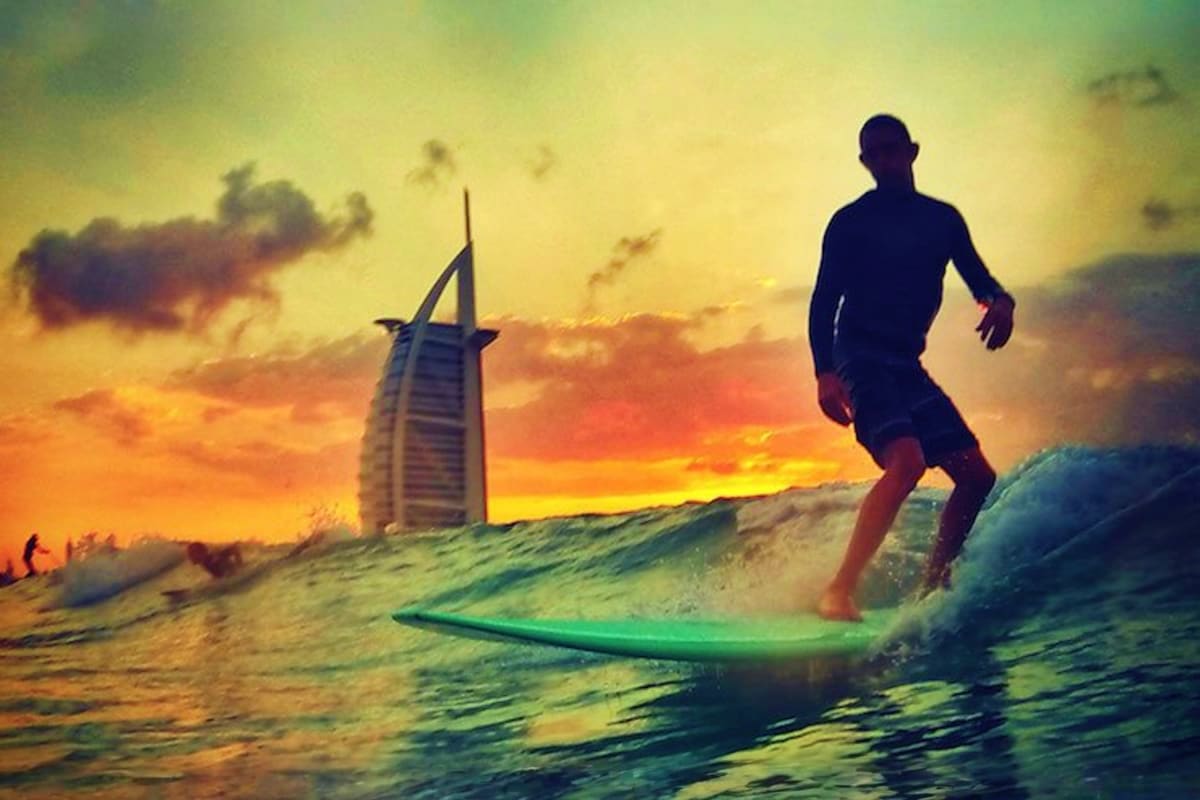 Man surfing on a large wave in clear turquoise ocean water under blue sky with white clouds (2)
