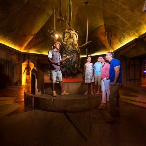Family viewing underwater tunnel at aquarium with yellow and blue tanks visible in modern facility (3)