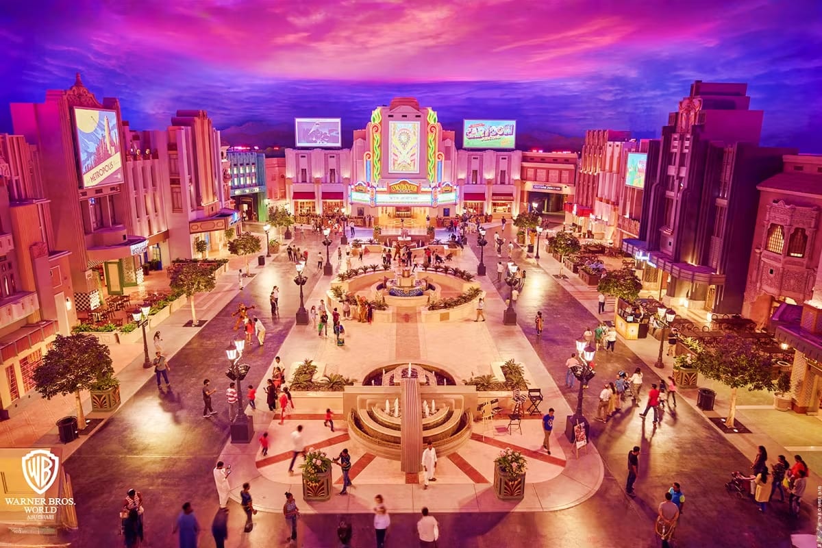 Family entering bright yellow Warner Bros World theme park entrance with blue glass facade and character banners under clear (4)