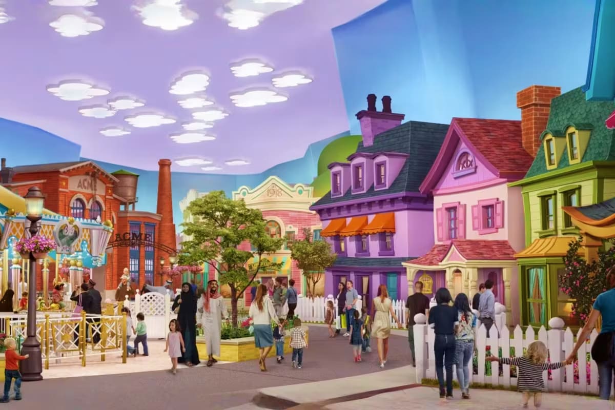 Family entering bright yellow Warner Bros World theme park entrance with blue glass facade and character banners under clear (5)