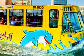 Yellow amphibious Wonder Bus with blue whale design driving into water during Dubai tour