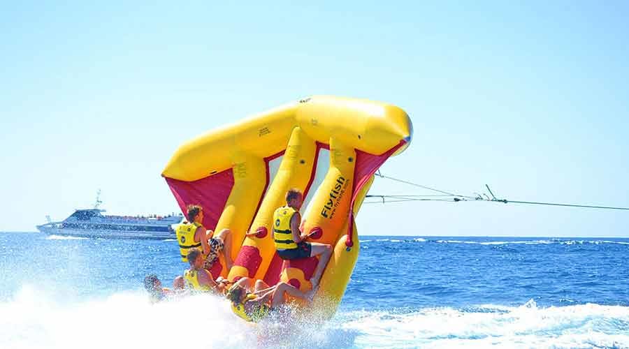 Family enjoying banana boat ride on blue water with yellow inflatable tube (4)
