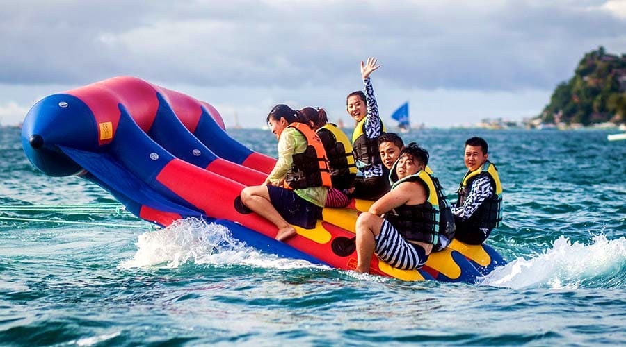 Family enjoying banana boat ride on blue water with yellow inflatable tube (2)