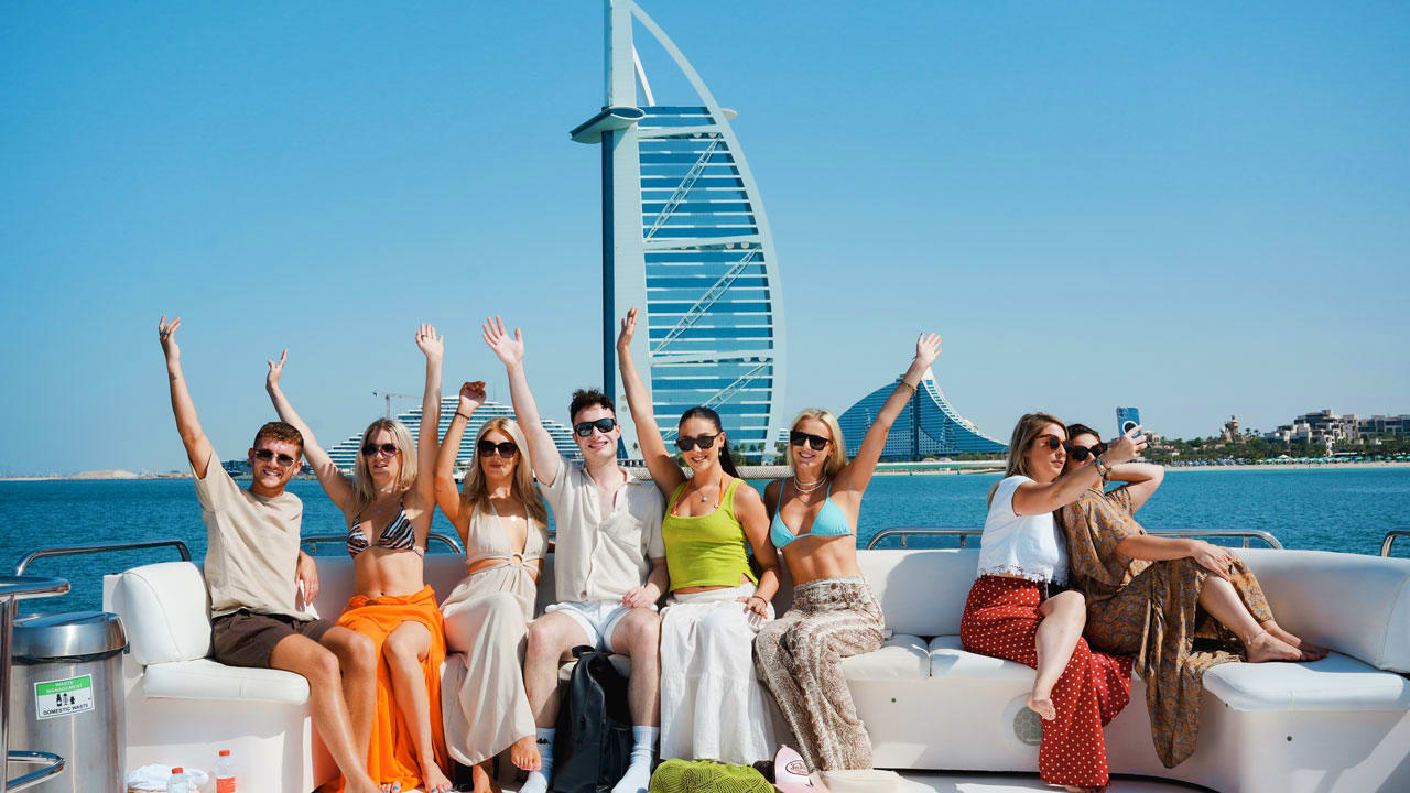 Group of tourists enjoying a shared yacht tour with skyline and water in background (3)