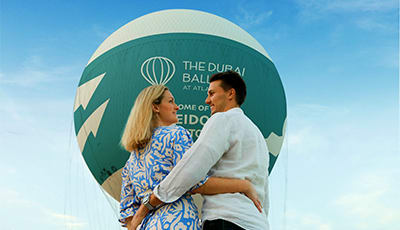 The Dubai Balloon at Atlantis Couple embracing inside The Dubai Balloon at Atlantis with green and white balloon envelope visible against blue sky