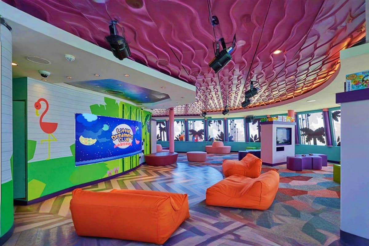 Colorful kids' club interior on Genting Dream cruise with purple wavy ceiling, orange bean bags, interactive screen, and brig