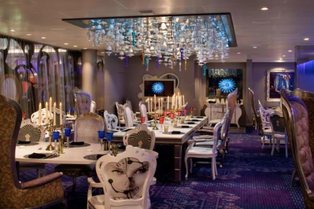 Elegant dining room on Spectrum of the Seas with long white tables, modern chandelier, decorative cat sculptures, and blue am