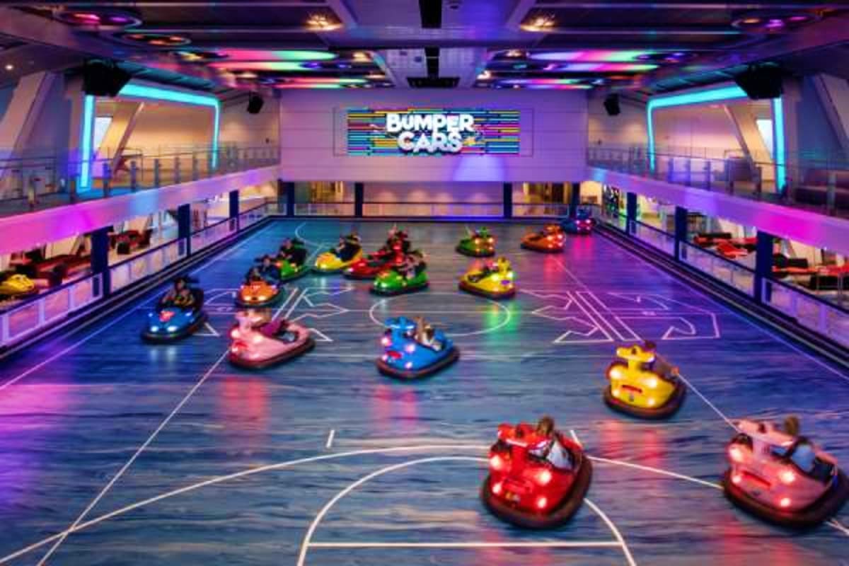 Colorful bumper cars arena with neon lighting and "Bumper Cars" sign, indoor entertainment venue on cruise ship