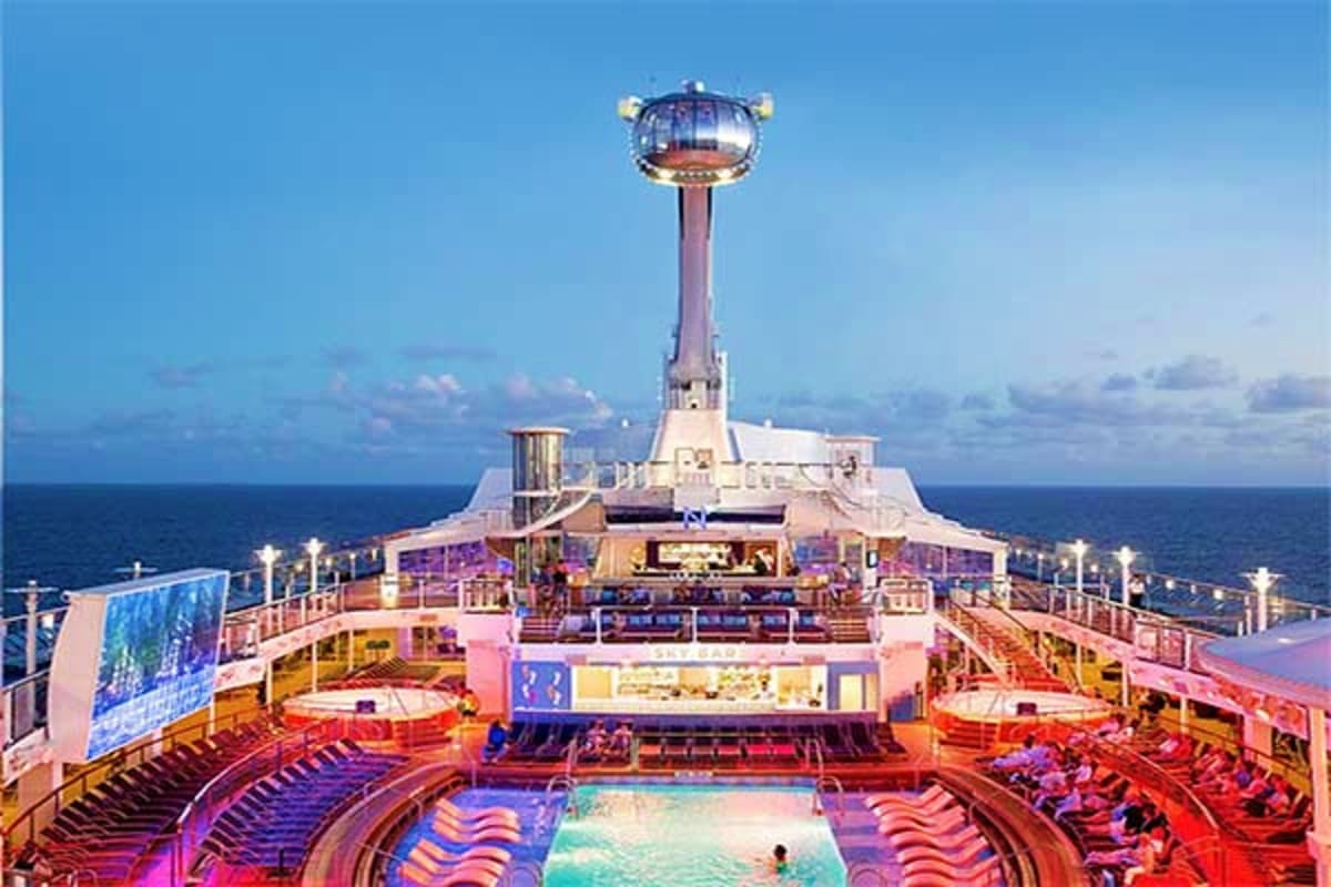 Aerial view of Spectrum of the Seas cruise ship deck with swimming pool, lounge chairs, and observation tower against ocean a