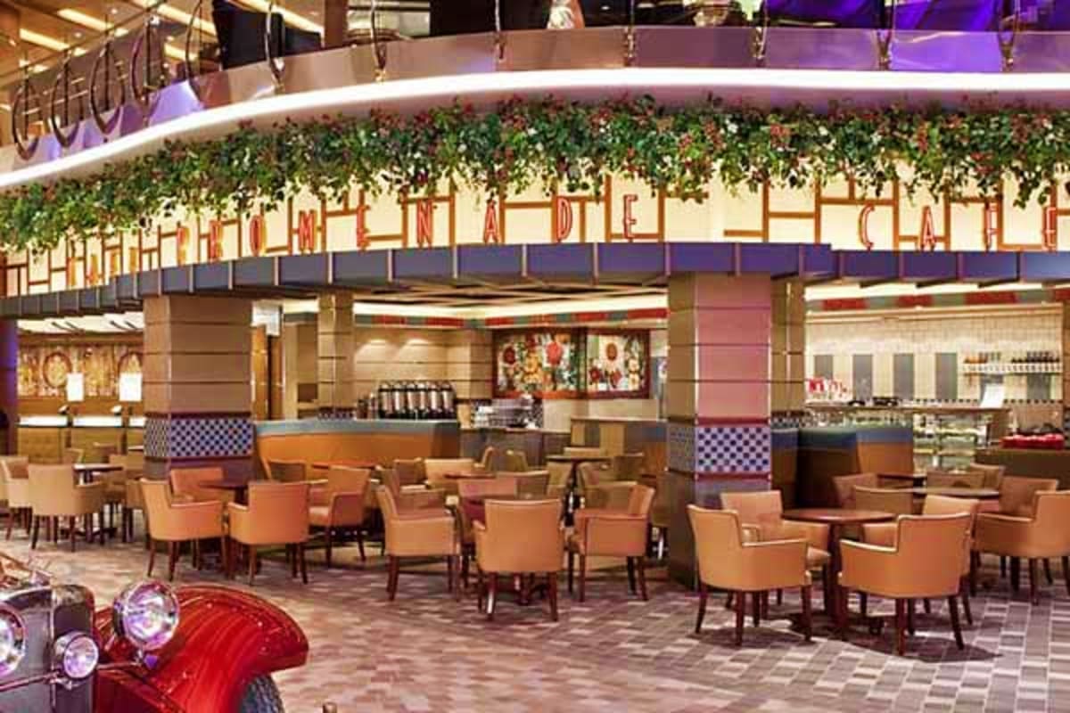Modern cruise ship dining venue with tan upholstered chairs, service counter with checkered pattern details, and decorative i