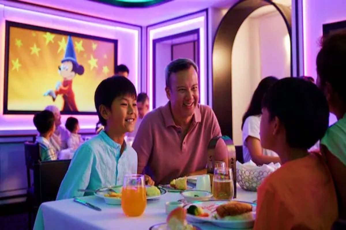 Three Nights Magical Disney Getaway Family dining together in animated-themed restaurant with purple neon lighting and Disney character display on wall
