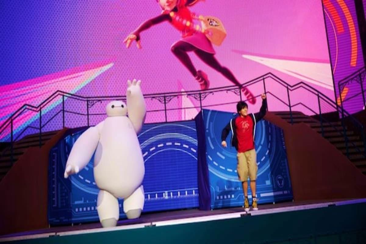 Child waving at large white inflatable character on Disney cruise ship deck with animated character projection on pink screen