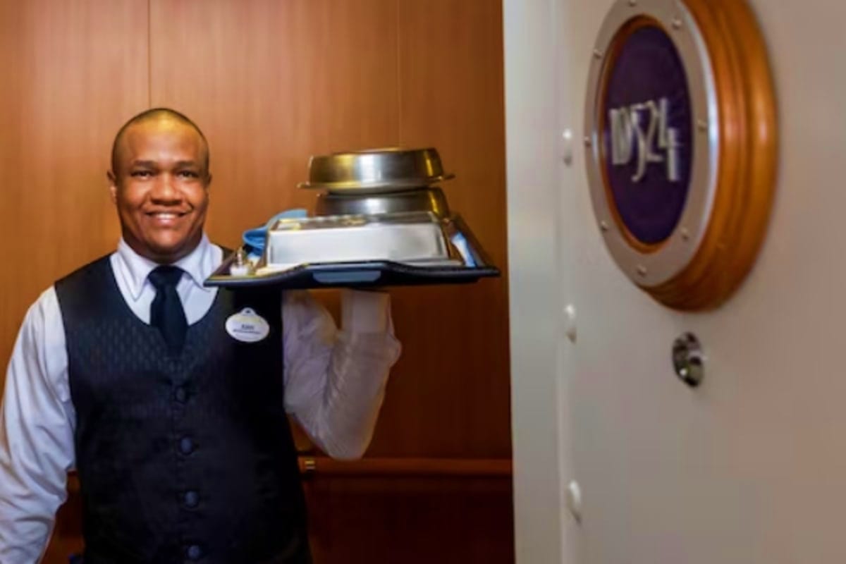 Magical Singapore and Langkawi Escape Professional server in formal vest and tie holding a silver tray with drinks outside a cruise ship cabin door