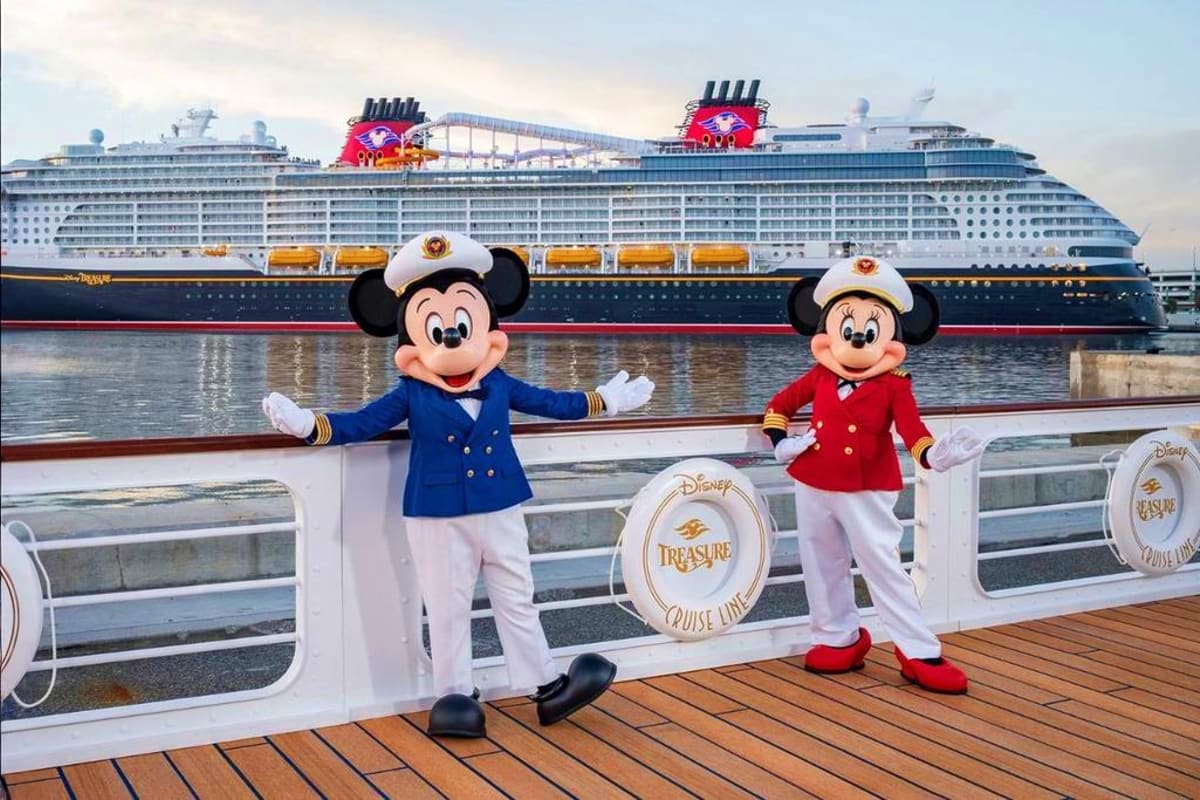 Mickey and Minnie Mouse in captain uniforms on Disney Treasure cruise ship deck, waving to camera