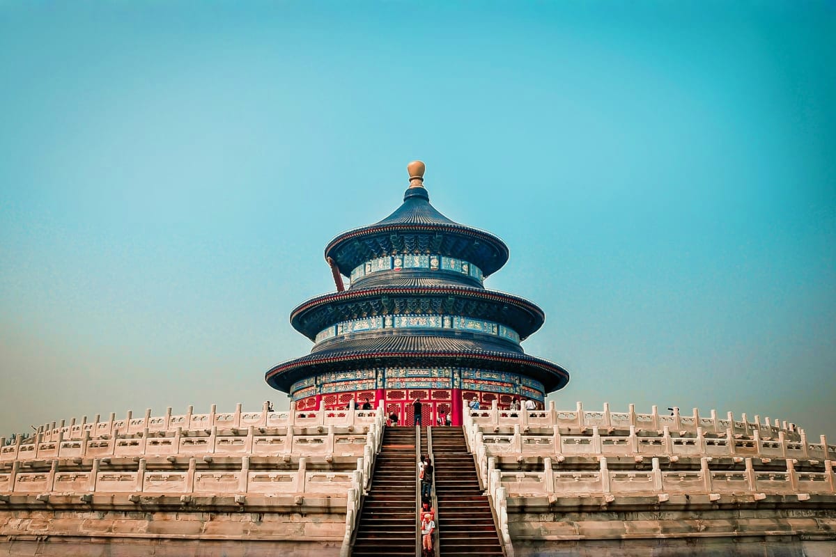Temple of Heaven in Beijing with three-tiered circular roof, red doors, and marble balustrade under clear blue sky