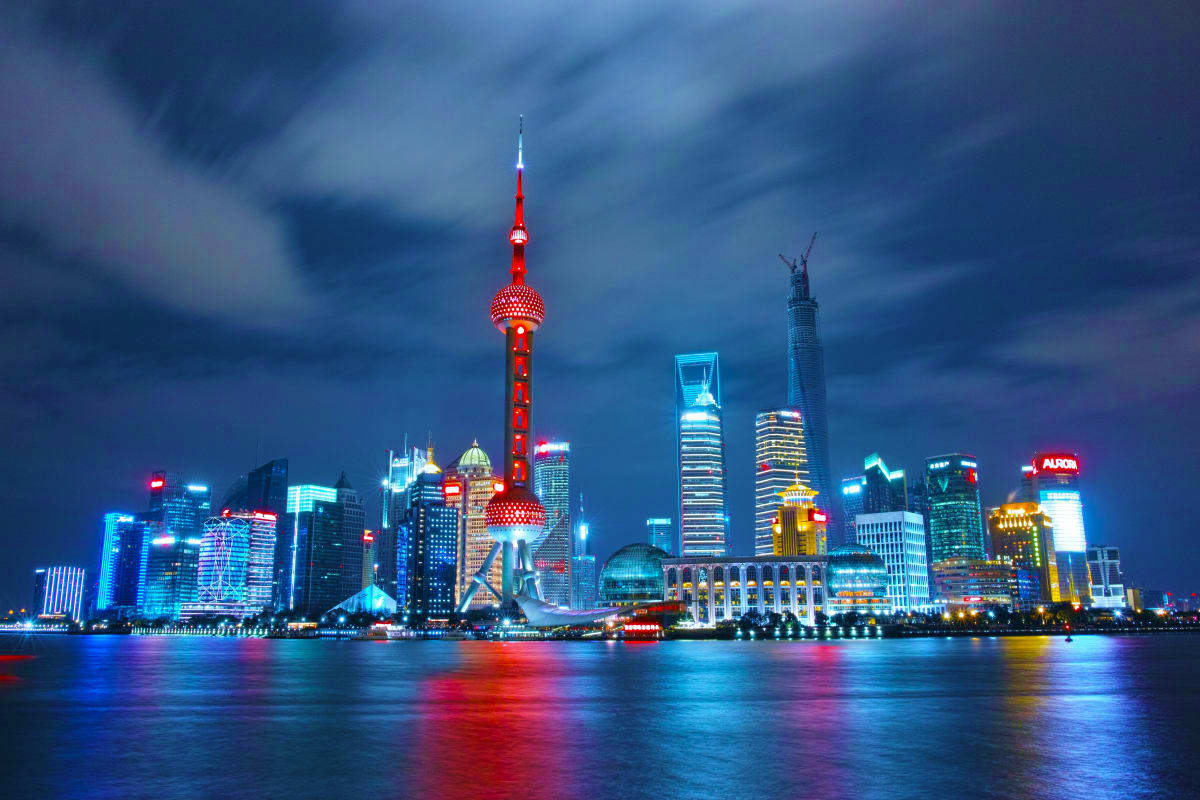 Shanghai skyline at night with illuminated Oriental Pearl Tower and modern skyscrapers reflected in the Huangpu River